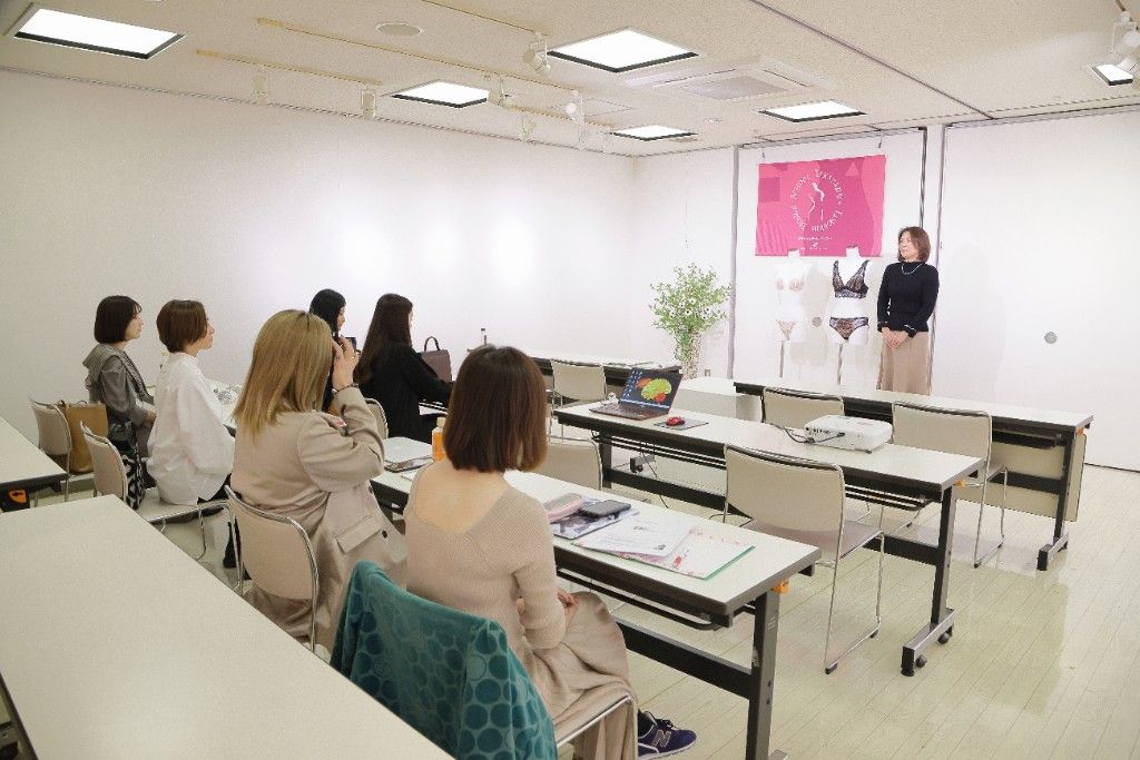 教室で講師の話を聞き、作品を見ながら学ぶ様子